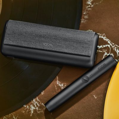 A Jade Green IQOS ILUMA PRIME Holder and Pocket Charger in a person's hands.