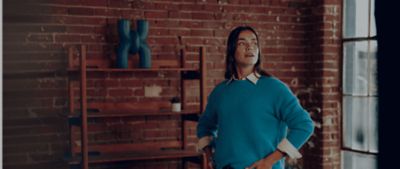 Mujer parada en la mitad de una sala con un IQOS ILUMA i en la mano.