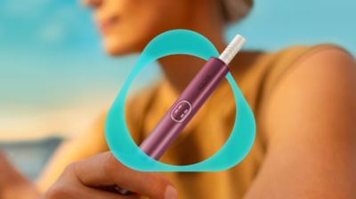 Woman holding a Garnet Red IQOS ILUMA i PRIME device