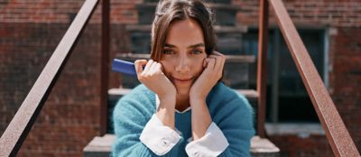 A smiling woman holding an IQOS device.