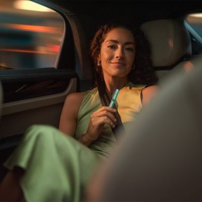 Dos mujeres en un auto sosteniendo un IQOS Iluma en la mano