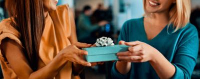 EIne Frau überreicht einer weiteren Frau ein Geschenk