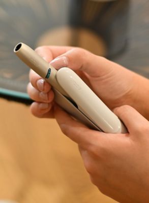 Hand entnimmt Holder aus IQOS ORIGINALS DUO Silver Pocket Charger.