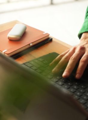 IOS ORIGINALS DUO Silver liegt neben Laptop auf Schreibtisch.