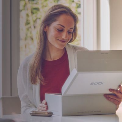 Hombre manejando su carro, una mujer coo pasajera esta usando IQOS