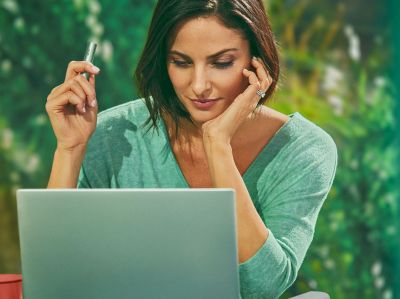 Mujer utilizando su computador mientras sostiene un IOQS iluma