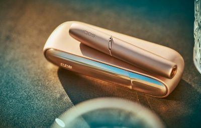 Appareil IQOS doré posé sur une surface claire 