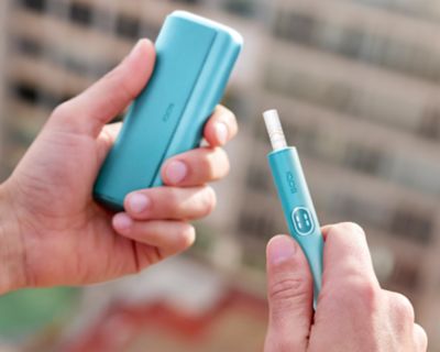 Close up of hands sharing an IQOS ILUMA device.