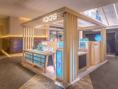 Estructura decorativa IQOS ILUMA hecha de madera clara con mostradores.