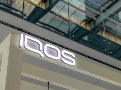 Letrero luminoso IQOS en estructura metálica dentro de tienda.