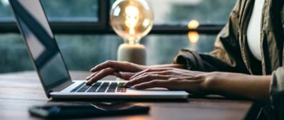 Eine Hand am Laptop auf einem Schreibtisch