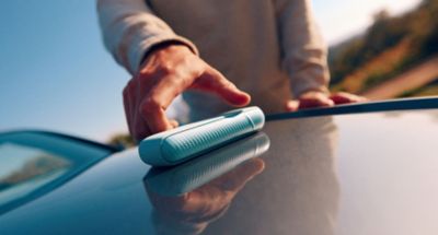 Hand greift nach einem IQOS ILUMA i in der Farbe Breeze Blue