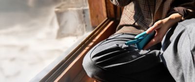 Frau entnimmt Holder aus IQOS ORIGINALS DUO Pocket Charger in der Farbe Turquoise.