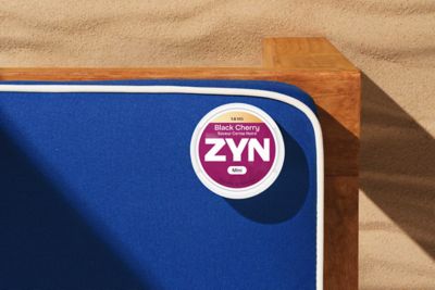 Une boîte de nicotine pouches ZYN Black Cherry 1.5MG, saveur Cerise Noire, posée sur un fond bleu.