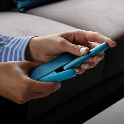 Person entnimmt IQOS ORIGINALS DUO Turquoise Holder aus Pocket Charger.