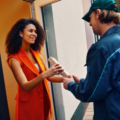 Žena v ruce drží zásilku IQOS před svými dveřmi domu