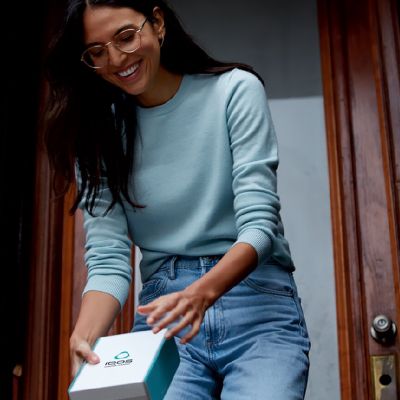 Žena v ruce drží zásilku IQOS před svými dveřmi domu