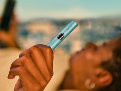 Zařízení IQOS ILUMA i v ruce, žena s naušnicí v pozadí