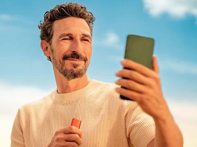 Muž držící telefon a zařízení IQOS ILUMA i ONE v  ruce