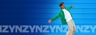 Muž v bílé košili a zelené mikině poslouchající hudbu