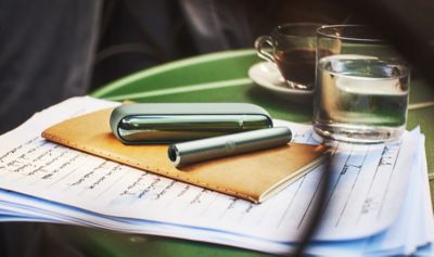 IQOS ILUMA Moss Green ležící na stole