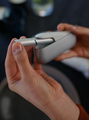 Close-Up zweier Hände, die ein IQOS ORIGINALS DUO Silver bedienen.