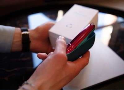 Close-Up zweier Hände beim Auspacken eines IQOS ORIGINALS DUO-Geräts in Turquoise.