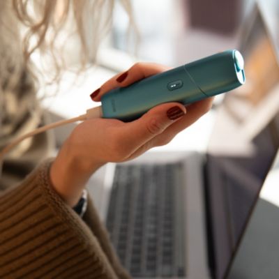 Eine Fraue hält ien IQOS Gerät in der Hand