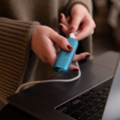 Ein IQOS wird gehalten und wird geladen