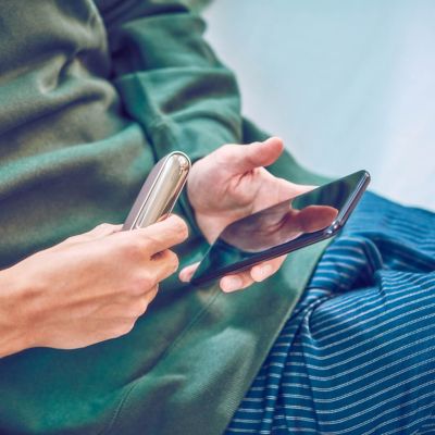 Mujer usando un dispositivo IQOS ILUMA mientras está sentada en el vehículo.