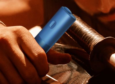 Hands holding a blue BONDS 2 by IQOS device