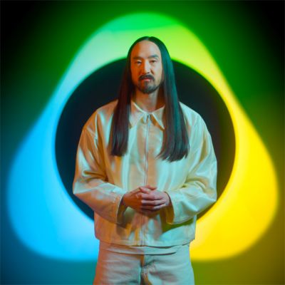 Steve Aoki in white dress in front of IQOS dedicated logo