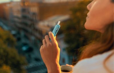 Woman holding IQOS ILUMA I ONE with stick inserted