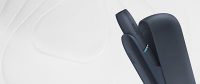 Ein schwarzes IQOS ORIGINALS DUO Gerät steht vor einem weißen Hintergrund mit geschwungenen Linien.
