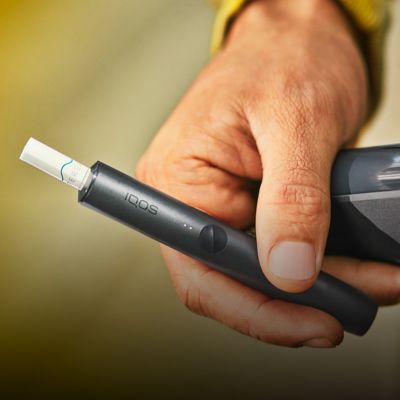 Hand hält schwarzen IQOS ILUMA Holder