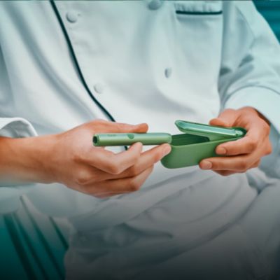 A Moss Green IQOS ILUMA Holder and Pocket Charger.