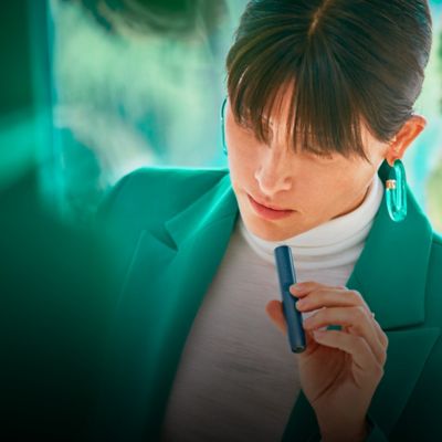 Mujer sosteniendo un dispositivo de tabaco calentado IQOS