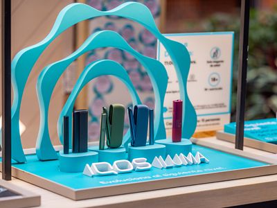 Dispositivos IQOS ILUMA en vitrina con estructura de arcos superpuestos.