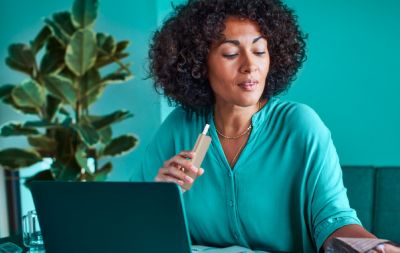 Lady with IQOS ILUMA One in hand and working with a laptop