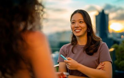 Lady with IQOS ILUMA One in hand and working with a laptop