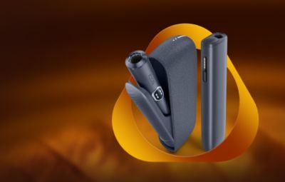 IQOS ILUMA i MID at ONE gris avec étui de recharge, présentés sur un fond dégradé noir et orange.