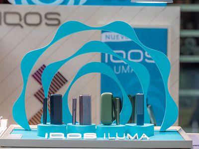 Panel frontal IQOS ILUMA con arco iluminado y dispositivos alineados.