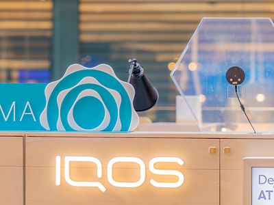 Arcos decorativos IQOS ILUMA con dispositivos exhibidos sobre base clara.