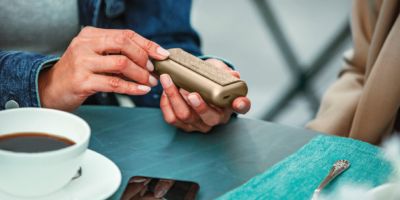 Hands holding a Jade Green IQOS ILUMA PRIME device