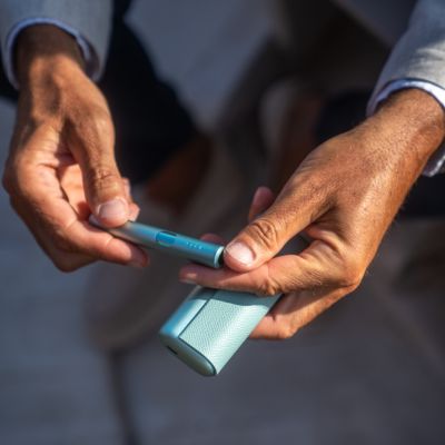 A Jade Green IQOS ILUMA PRIME Pocket Charger on a table.