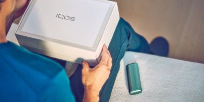 Una persona sosteniendo una caja cerrada de un dispositivo IQOS.