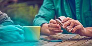 Eine Person sitzt am Tisch mit einem IQOS DUO in der Hand