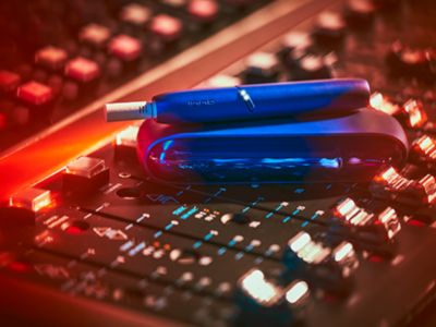 A woman kissing the cheek of a man who is holding an IQOS device .