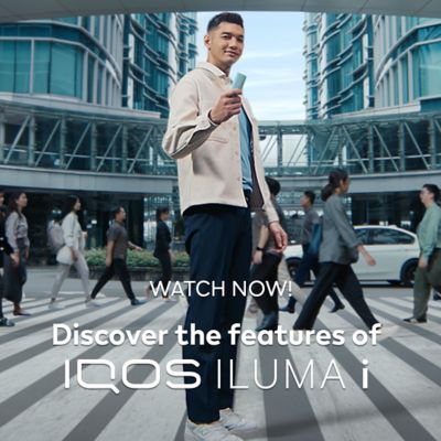 A person holding an IQOS Device in front of a building