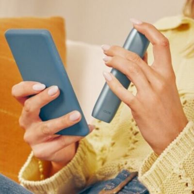 Mains tenant un téléphone portable et un IQOS Originals One